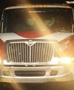 head-on view of the front of a red and white tow truck at night. The headlights are causing lens flare