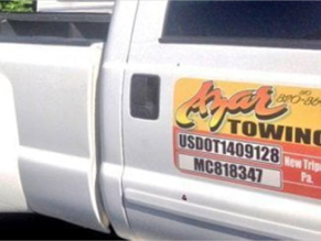 The passenger-side door of an Azar tow truck with it's certification numbers under the logo.