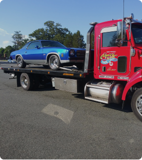 An Azar light-duty flatbed tow truck with a Chevrolet Chavelle chained to its bed.