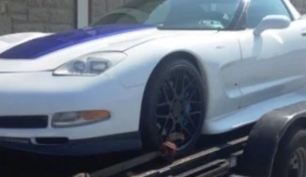 A white sports car rests on a flatbed tow.