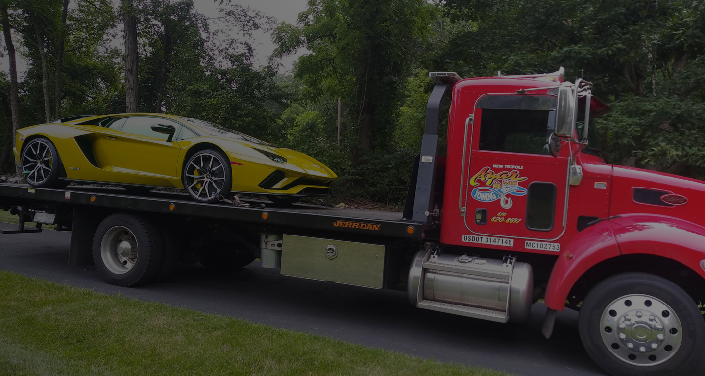 A yellow sportscar on the back of a red Azar flatbed pickup truck.