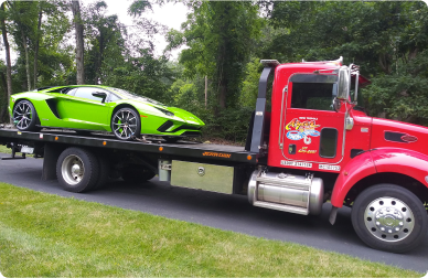 A green sportscar on the back of an Azar flatbed tow truck.