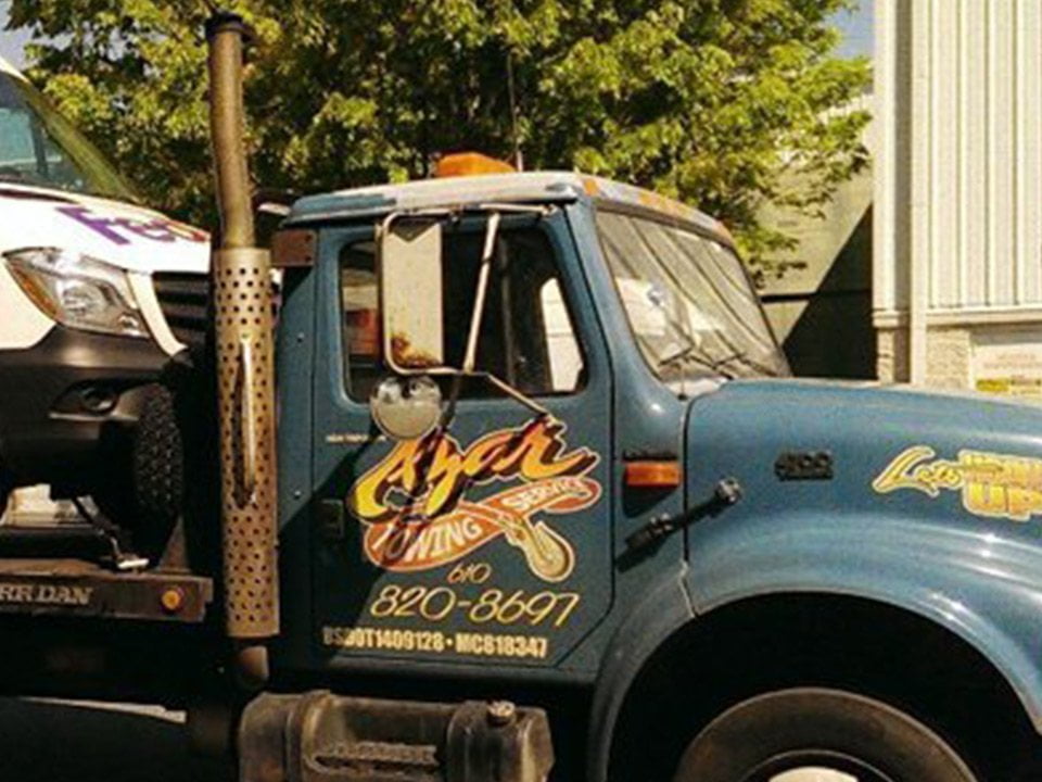 A blue-cabbed tow truck with the Azar logo hauls a FedEx van.