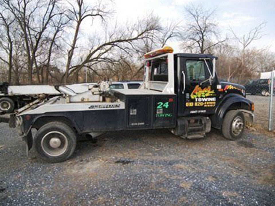 A black-cabbed Azar wheel-lift tow truck parked on a lot.